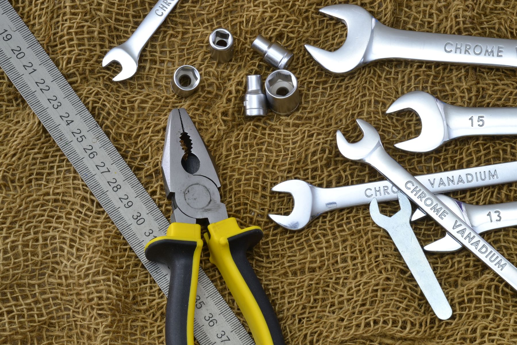 Wrenches, pliers and sockets laid out on a workbench