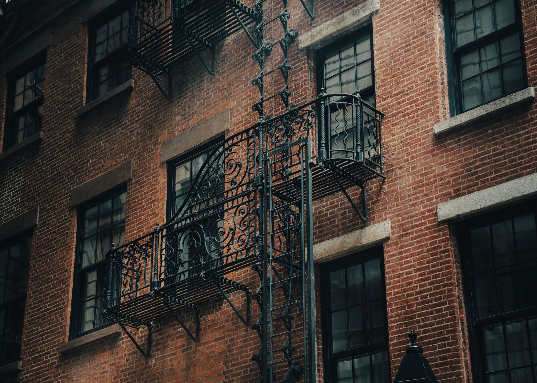 Ornate wrought-iron fire escape railing on a brick building